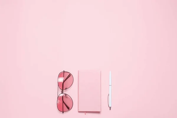 Diario rosa, gafas y bolígrafo sobre escritorio rosa. Asiento plano, vista superior. Copiar espacio — Foto de Stock