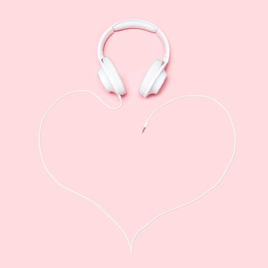 Kulaklıklar, pembe bir arka plan üzerinde bir kalp şeklinde bir kordon ile. Minimalist düz blogcular, tasarımcılar, dergi vb kopya alanı ile kompozisyon yatıyordu