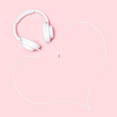 Kulaklıklar, pembe bir arka plan üzerinde bir kalp şeklinde bir kordon ile. Minimalist düz blogcular, tasarımcılar, dergi vb kopya alanı ile kompozisyon yatıyordu