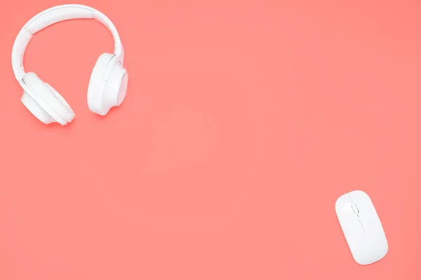 White Wireless headphones and wireless mouse on coral colored background. Top view. Flat lay — Stock Photo, Image