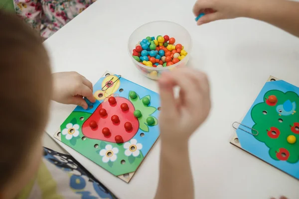 Peuters spelen veelkleurige educatieve spellen, mozaïek en puzzels tabel — Stockfoto