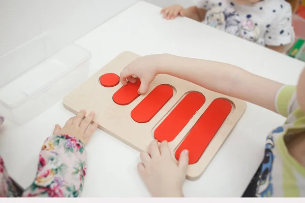 Peuters spelen veelkleurige educatieve spellen, mozaïek en puzzels tabel — Stockfoto