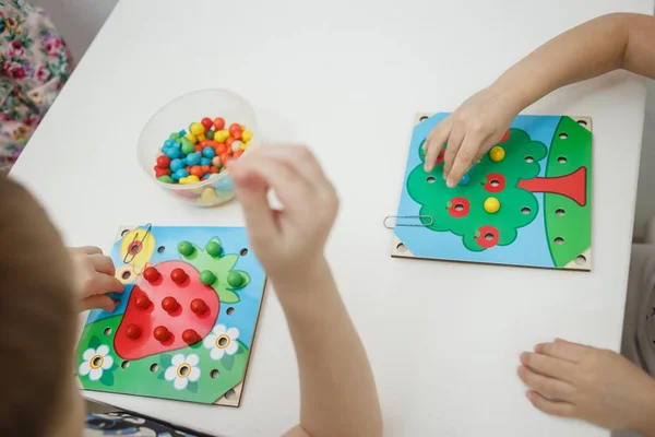 Peuters spelen veelkleurige educatieve spellen, mozaïek en puzzels tabel — Stockfoto