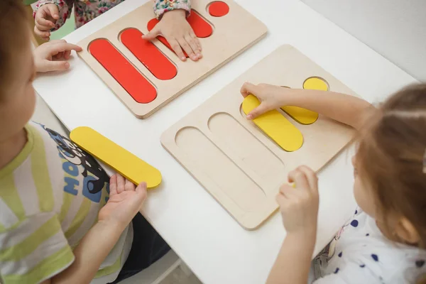 Småbørn spiller flerfarvede pædagogiske spil, mosaik og puslespil bord - Stock-foto