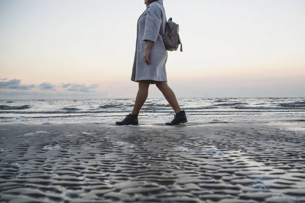 穿着外套走在海边的女人 — 图库照片