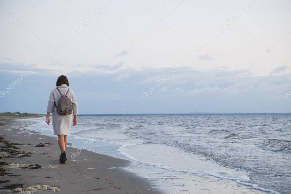 Woman in coat walking on the seashore