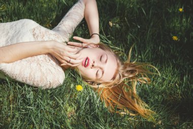 Yeşil çimenlerin üzerinde güneşli gün zevk beyaz dantel elbise güzel sarışın