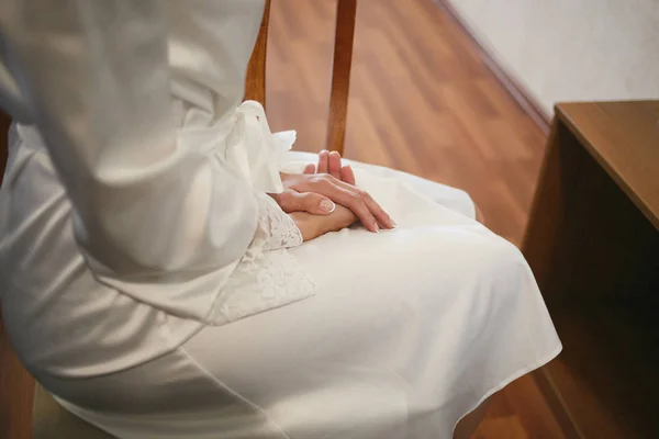 La chica se sienta en una silla, cruzando las manos con una manicura perfecta. La mañana de boda de la novia — Foto de Stock