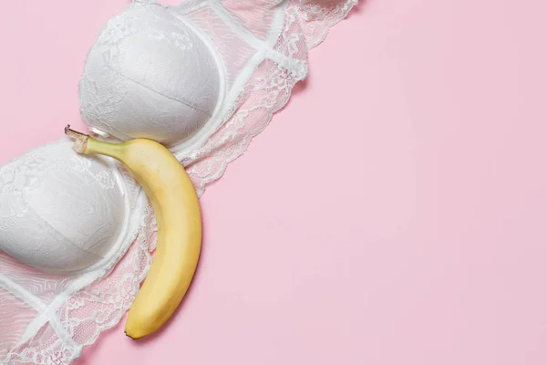 Conversa erótica, conceito de sexo virtual. Sutiã branco e banana grande em um fundo rosa. Deitado plano minimalista, vista superior — Fotografia de Stock