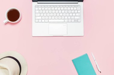 Laptop, yaz şapka, fincan kahve, Akuamarin defter ve kalem şık pembe tablo. Üstten Görünüm. Kopya alanı ile düz lay şablon