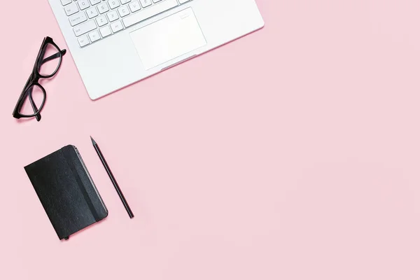 Trendy Pink table with laptop, black, eyeglasses, black notebook and pencil. Вид сверху. Плоский шаблон с копировальным пространством — стоковое фото