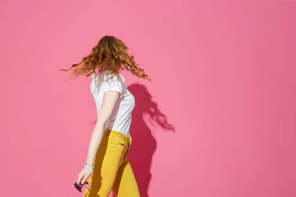 Mulher loira alegre em camiseta branca e jeans amarelos na moda dançando em fundo rosa — Fotografia de Stock