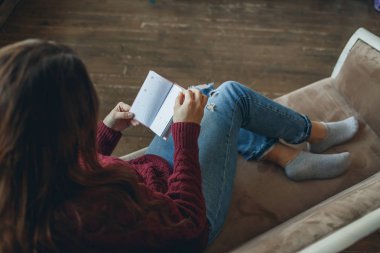 Genç kadın kanepe günlüğünü okuma