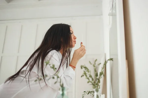 Mulher branca bonita aplicando maquiagem no quarto brilhante — Fotografia de Stock