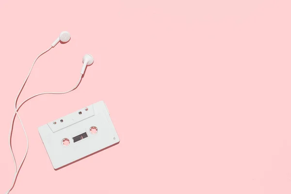 Cinta de casete blanca y auriculares sobre fondo rosa — Foto de Stock