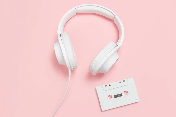 Cinta de casete blanca y auriculares sobre fondo rosa —  Fotos de Stock