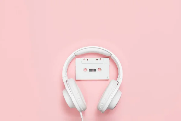 Cinta de casete blanca y auriculares sobre fondo rosa —  Fotos de Stock