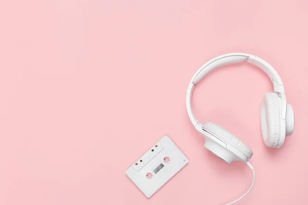 Cinta de casete blanca y auriculares sobre fondo rosa —  Fotos de Stock