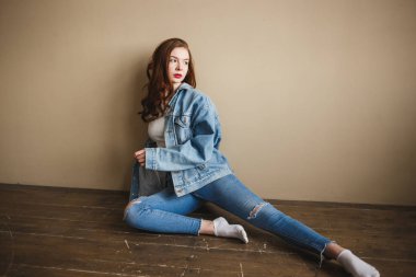 Denim Ceket Poz Şehvetli Kadın Model, Kot Pantolon ve Bej Duvar yakınındaki Katta Beyaz Çorap. Geri 1990'larda Moda Lifestyle Style Concept