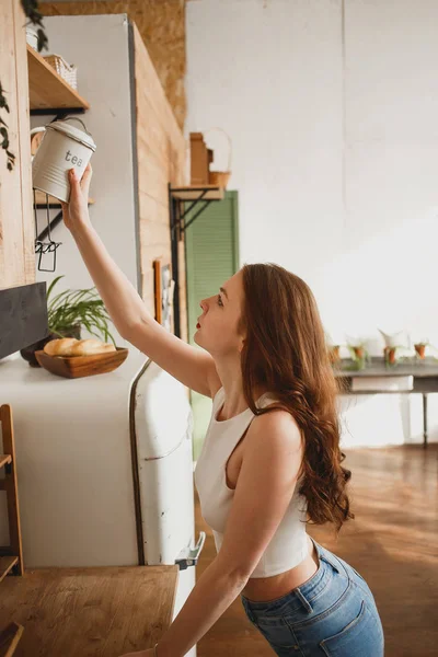 Jovem na cozinha segurando lata de chá — Fotografia de Stock