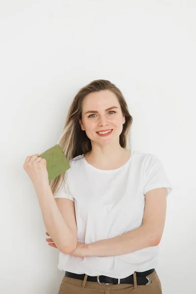 Retrato de mujer sonriente con éxito en ropa casual con libro verde sobre fondo claro —  Fotos de Stock