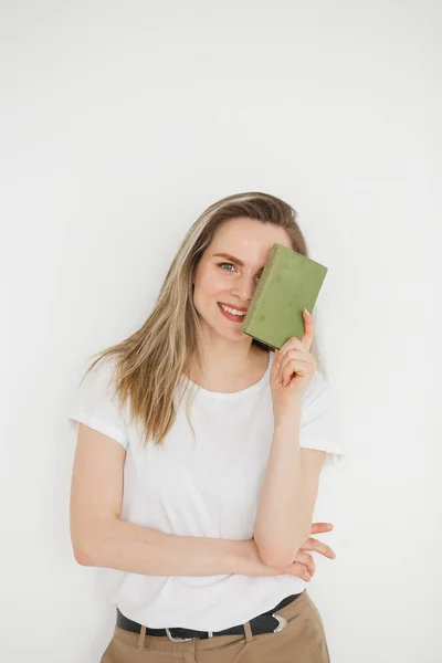 Retrato de mujer sonriente con éxito en ropa casual con libro verde sobre fondo claro —  Fotos de Stock