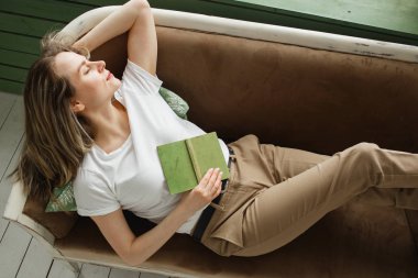 Kanepe üzerinde yeşil kitap ile uyuyan güzel kadın