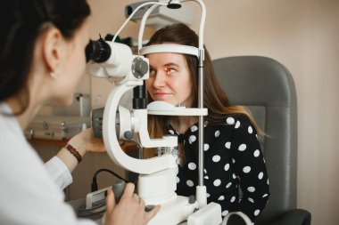 Arkhangelsk, Rusya-25 Mart 2019: çekici kadın doktor Oftalmolog modern klinikte genç kadının göz vizyonu kontrol ediyor. Doktor ve hasta Oftalmoloji Kliniği