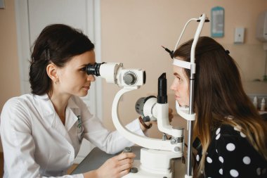 Arkhangelsk, Rusya-25 Mart 2019: çekici kadın doktor Oftalmolog modern klinikte genç kadının göz vizyonu kontrol ediyor. Doktor ve hasta Oftalmoloji Kliniği