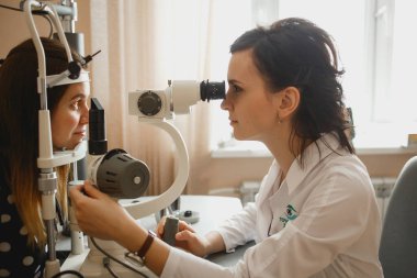 Arkhangelsk, Rusya-25 Mart 2019: çekici kadın doktor Oftalmolog modern klinikte genç kadının göz vizyonu kontrol ediyor. Doktor ve hasta Oftalmoloji Kliniği