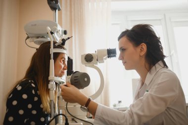 Arkhangelsk, Rusya-25 Mart 2019: çekici kadın doktor Oftalmolog modern klinikte genç kadının göz vizyonu kontrol ediyor. Doktor ve hasta Oftalmoloji Kliniği
