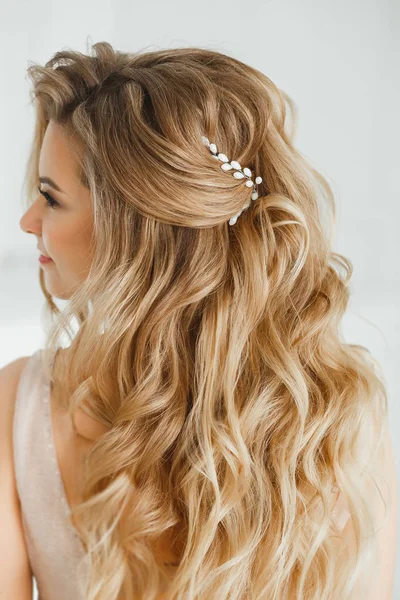 Belle femme blonde montrant sa coiffure grecque parfaite et boucles d'oreilles en cristal de couleur pourpre avec des perles. en beige posant en studio — Photo