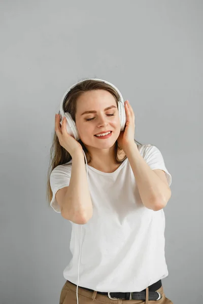 Užij si hudbu. Šťastná mladá žena potěšující hudbu v bílých sluchátkách. — Stock fotografie