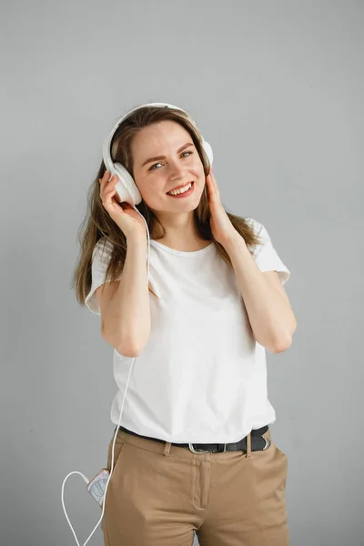 Užij si hudbu. Šťastná mladá žena potěšující hudbu v bílých sluchátkách. — Stock fotografie