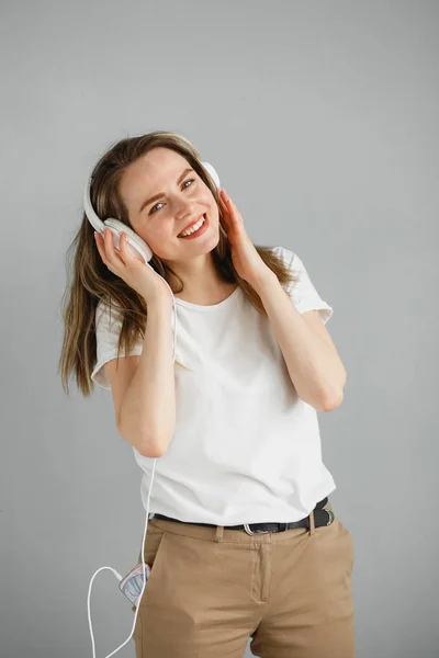 Müziğin tadını çıkar. Mutlu genç bir kadın beyaz kulaklıklarla müzik dinliyor.. — Stok fotoğraf