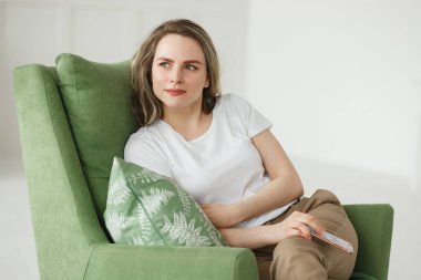 Hafif oturma odasında koltukta oturan telefon ile güzel genç kadın Portresi.