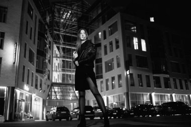 Zarif deri ceket ceket ve yüksek topuklu şehir sokakta yürüyüş gizemli kızıl saçlı kadın, noire atmosfer, ilginç kavramı