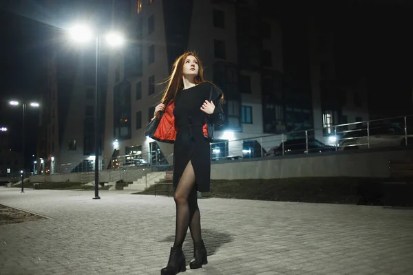 Tajemná zrní žena v elegantním koženém kabátě a vysokých podpatcích, chodící do městské ulice, Noire atmosféra, fascinující představa — Stock fotografie