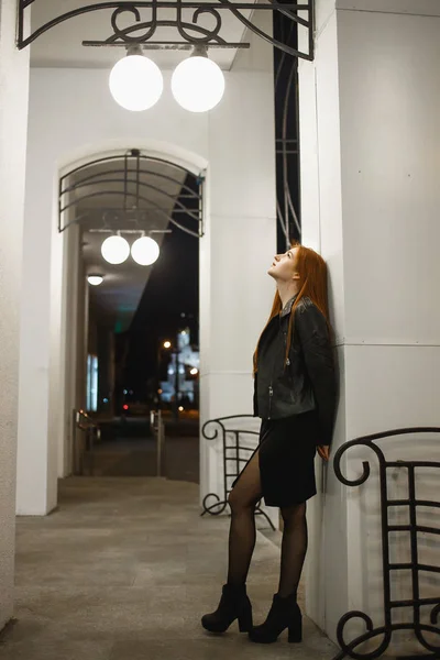 Zarif deri ceket ceket ve yüksek topuklu şehir sokakta yürüyüş gizemli kızıl saçlı kadın, noire atmosfer, ilginç kavramı — Stok fotoğraf