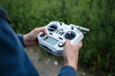 Quadrocopter için uzaktan kumanda, yakın çekim. Erkek elinde hareketli cihazı kontrol etmek için verici, bulanık doğa arka plan. Elektronik, hobi, aeromodelling kavramı. Özel yapım
