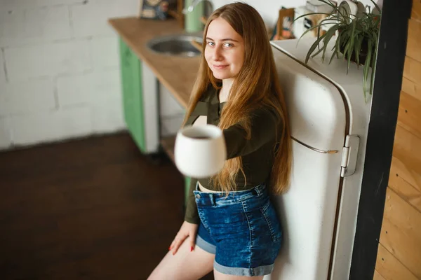 Hermosa joven pelirroja bebiendo té en la cocina por la mañana — Foto de Stock