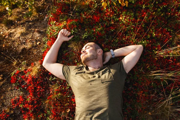 Сезон, счастье и концепция людей - улыбающийся молодой человек лежит на земле или траве, мох и опавшие листья в осенней тундре — стоковое фото