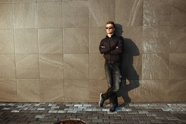 Selbstbewusster und gutaussehender junger Mann, der in der Nähe von Betonmauern steht. Außenporträt in voller Länge. Streetstyle-Halbjahreskleidung — Stockfoto