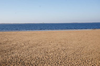 Minimalist manzara boş kumsal ve sonbaharda güneşli bir günde derin mavi su.