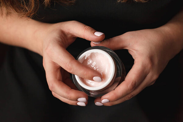 Красивая женщина руки со сливками на темном фоне
