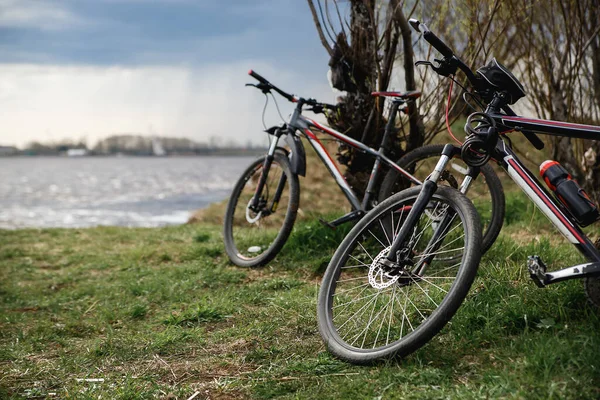 Two mountain bikes stand on the river bank. Atmospheric dynamic light. Picnic — Stock Image Two mountain bikes stand on the river bank. Atmospheric dynamic light. Picnic Royalty Free Stock Photos