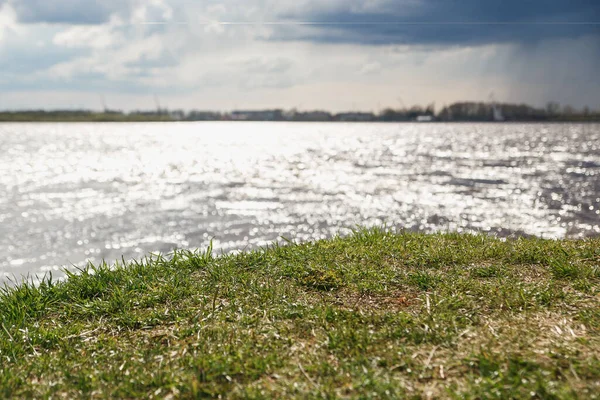 The concept of changeable cloudy windy and rainy weather luscious green grass on the river bank in the background — Stock Image The concept of changeable cloudy windy and rainy weather luscious green grass on the river bank in the background Stock Image