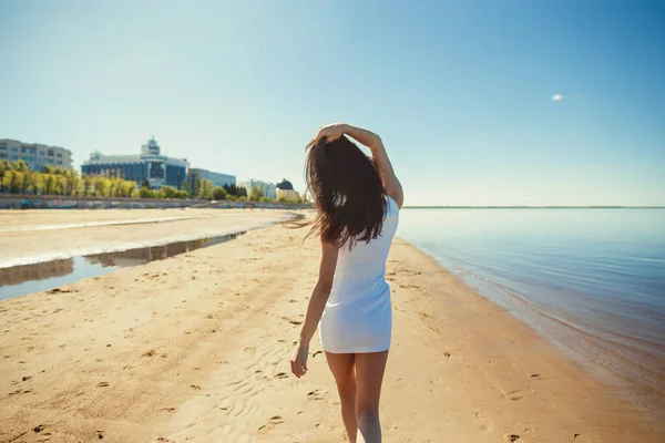 Porträt der schönen sexy glückliches Mädchen am Strand der Sandstadt mit Meereshintergrund. Junge lächelnde Frau, die Spaß hat, flirtet und gegen blauen Himmel und Wasser tanzt. Unbekümmertes Sommerkonzept — Stockfoto