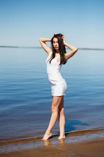 Young sexy lady in the white dress standing in the warm water — ストック写真