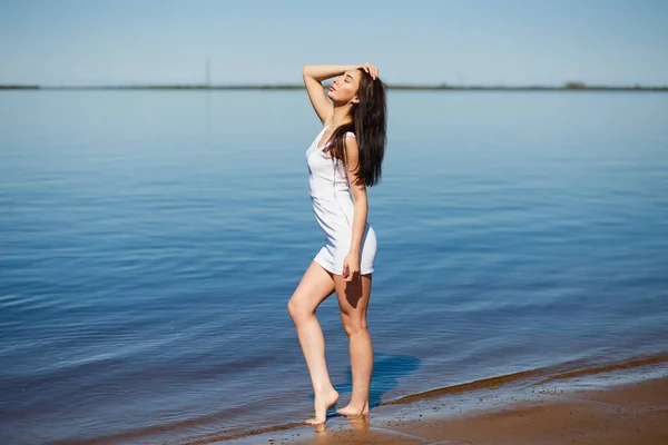 Молодая сексуальная леди в белом платье, стоящая в теплой воде — стоковое фото
